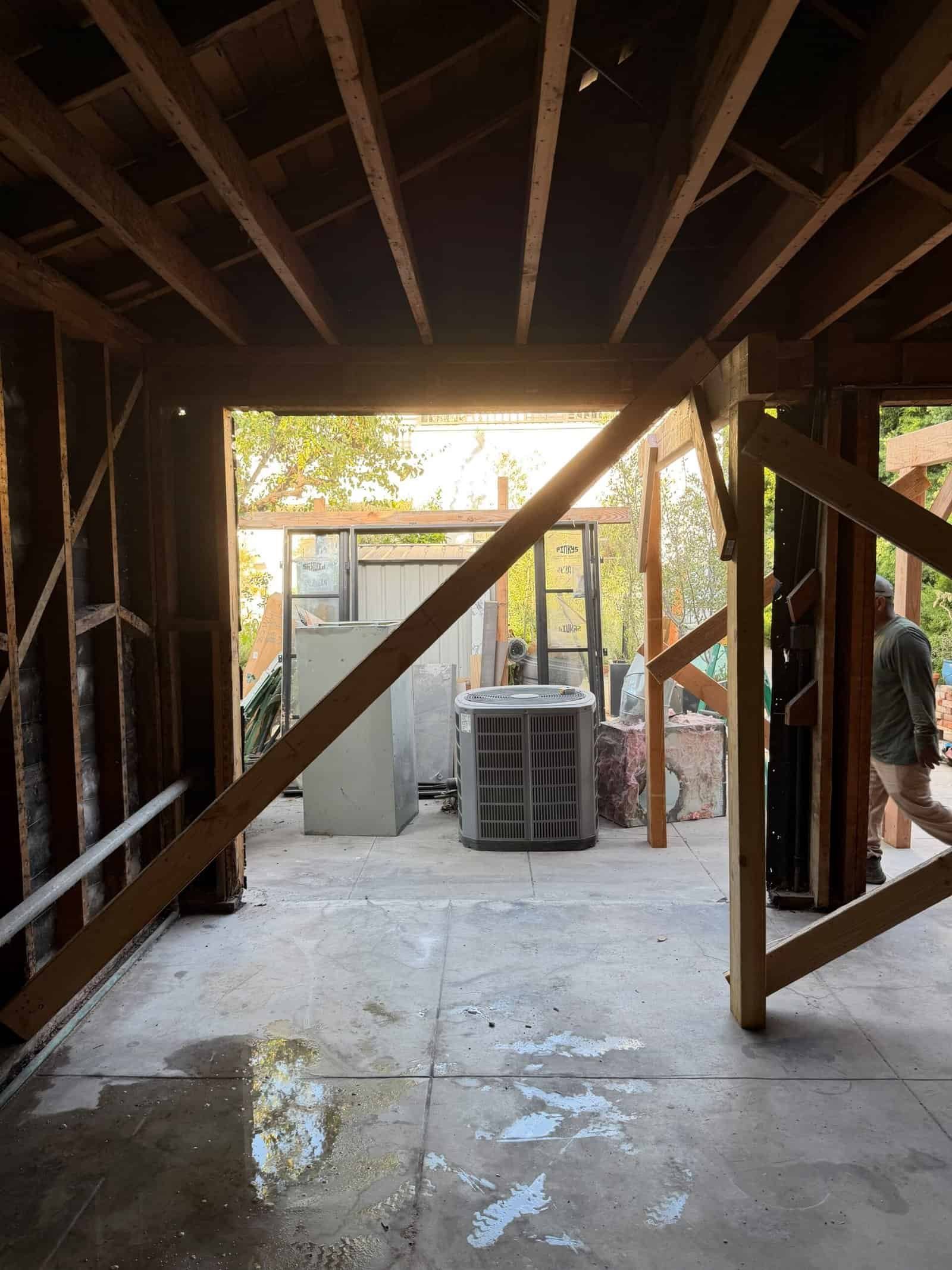 View from inside a building under construction showing framing and outdoor equipment.