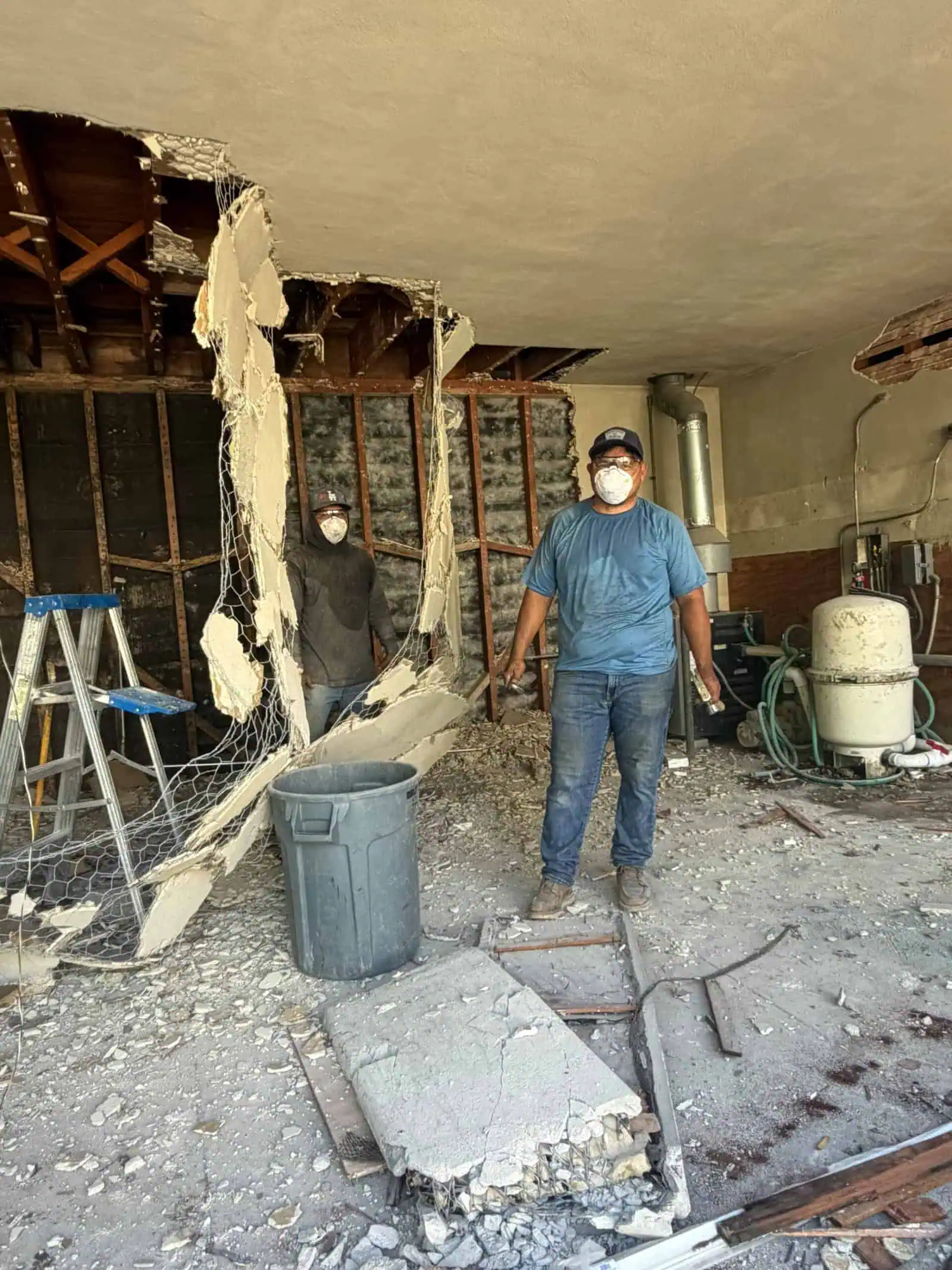 Construction workers in protective masks working on interior demolition.