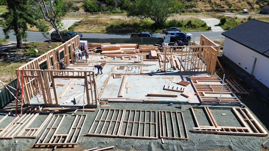 Wooden framing for building under construction with workers on site.