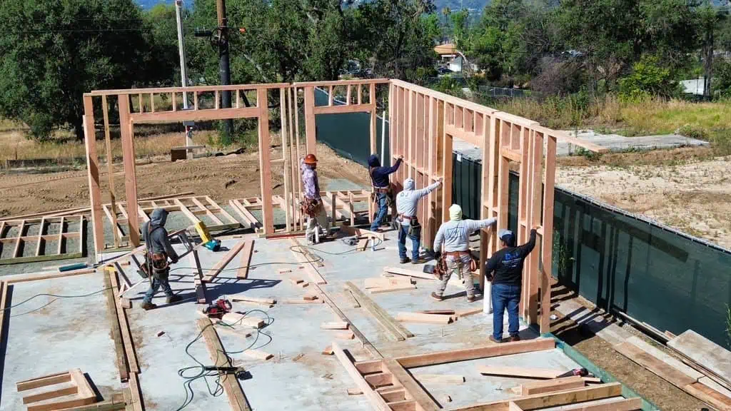 Construction workers assembling wooden building frame at a site.