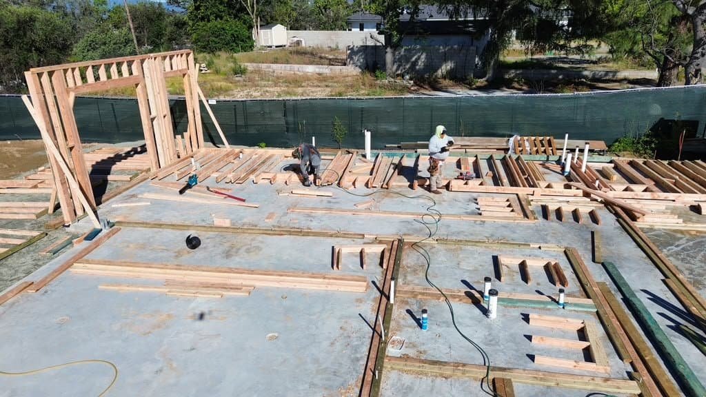 Construction workers building a wooden house frame on site.